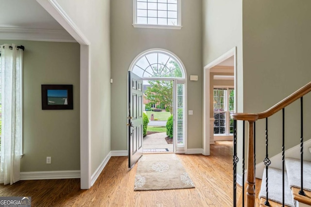 6695 Buckingham Cir, Cumming, GA 30040 - entryway featuring plenty of natural light, wood finished floors, ornamental molding, a high ceiling, and stairs