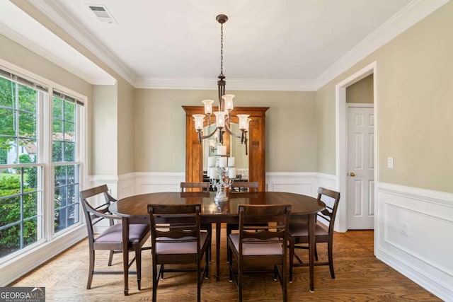 6695 Buckingham Cir, Cumming, GA 30040 - dining room featuring a chandelier, crown molding, a wainscoted wall, wood finished floors, and a decorative wall