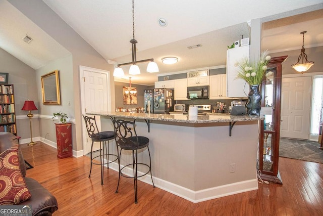 215 Fairway Ct, Newnan, GA 30265 - kitchen with appliances with stainless steel finishes, light stone countertops, a breakfast bar, wood finished floors, and vaulted ceiling