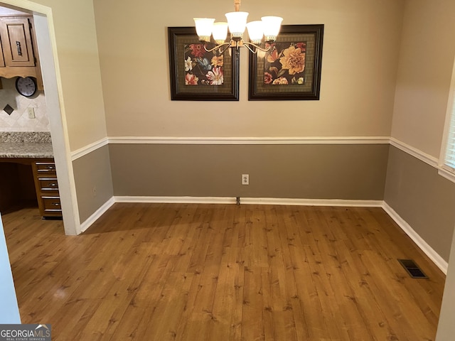 3788 Hartley Bridge Rd, Macon, GA 31216 - unfurnished dining area featuring wood finished floors, a chandelier, and baseboards