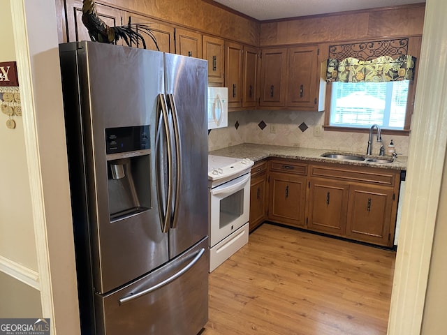 3788 Hartley Bridge Rd, Macon, GA 31216 - kitchen featuring white appliances, light wood finished floors, tasteful backsplash, light stone counters, and brown cabinetry