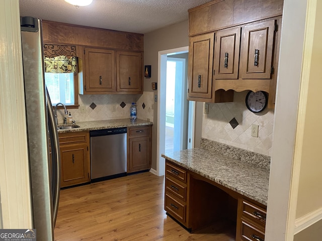 3788 Hartley Bridge Rd, Macon, GA 31216 - kitchen with appliances with stainless steel finishes, light wood-style flooring, decorative backsplash, brown cabinets, and a textured ceiling
