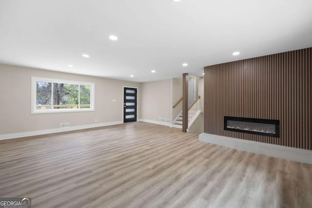 1120 Taliwa Trl NE, Marietta, GA 30068 - unfurnished living room with wood finished floors, recessed lighting, stairs, and a glass covered fireplace