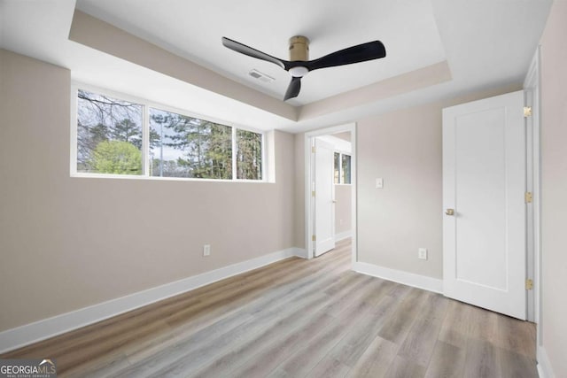 1120 Taliwa Trl NE, Marietta, GA 30068 - unfurnished bedroom featuring a tray ceiling, light wood-style floors, and ceiling fan