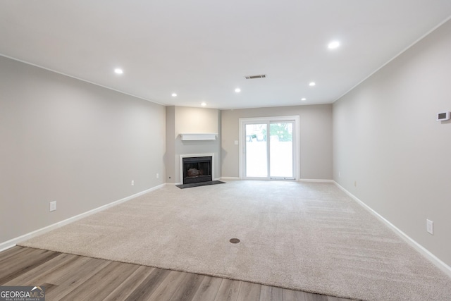 1017 Ridgefield Dr, Peachtree City, GA 30269 - unfurnished living room featuring a fireplace with flush hearth, baseboards, recessed lighting, light wood finished floors, and light carpet