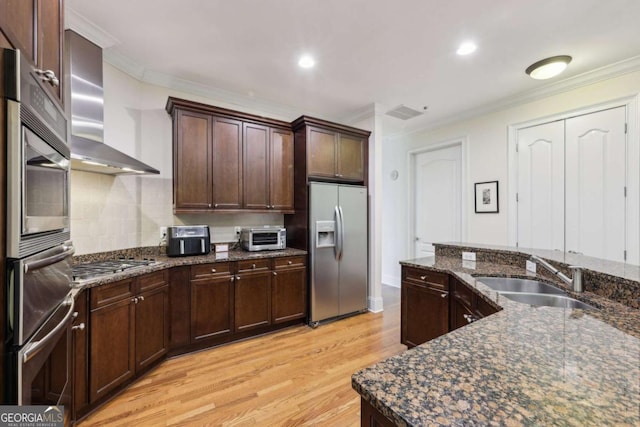 3280 Stillhouse Ln SE Unit 212, Atlanta, GA 30339 - kitchen featuring stainless steel appliances, wall chimney range hood, light wood-style floors, crown molding, and dark stone countertops