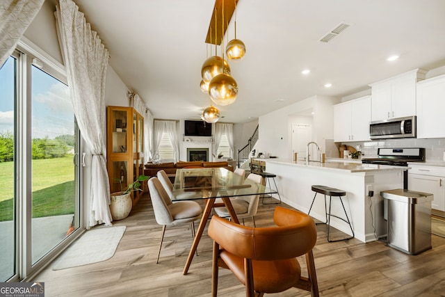 4720 Dufour Dr, Lilburn, GA 30047 - dining area featuring light wood-type flooring, a glass covered fireplace, and recessed lighting