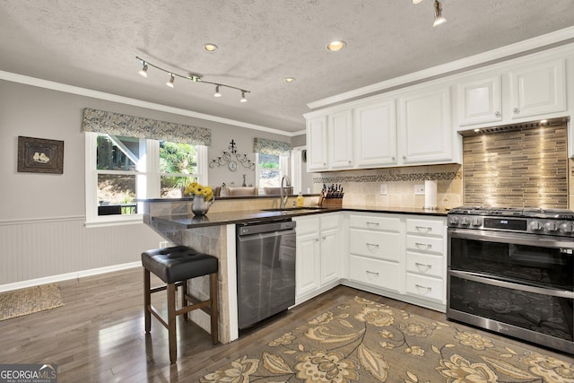 4320 Oklahoma Way NW, Kennesaw, GA 30152 - kitchen with stainless steel appliances, a sink, crown molding, a peninsula, and dark wood-style flooring