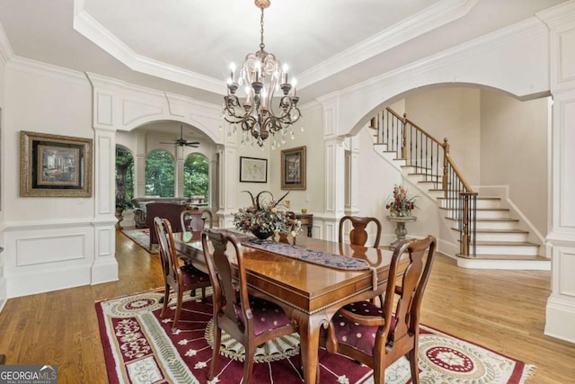 8970 Moor Park Run, Duluth, GA 30097 - dining room featuring arched walkways, light wood finished floors, decorative columns, stairs, and crown molding