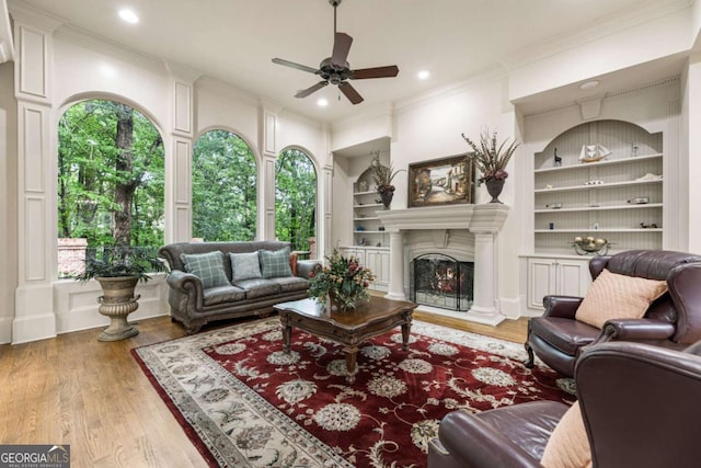 8970 Moor Park Run, Duluth, GA 30097 - living area with built in features, ceiling fan, wood finished floors, crown molding, and a lit fireplace