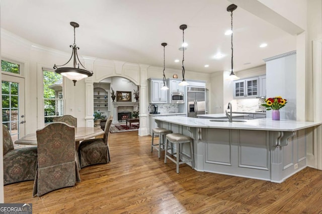 8970 Moor Park Run, Duluth, GA 30097 - kitchen featuring appliances with stainless steel finishes, a kitchen breakfast bar, wood finished floors, a peninsula, and crown molding