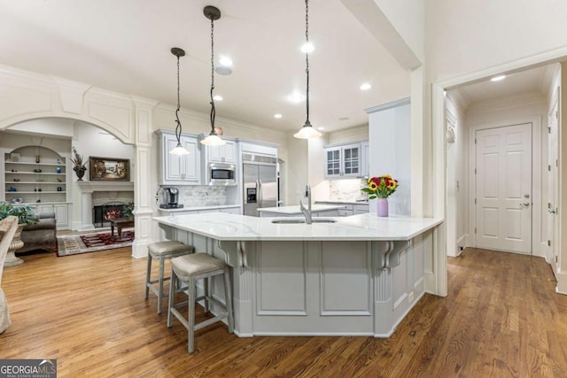 8970 Moor Park Run, Duluth, GA 30097 - kitchen featuring built in appliances, wood finished floors, a kitchen bar, backsplash, and a peninsula