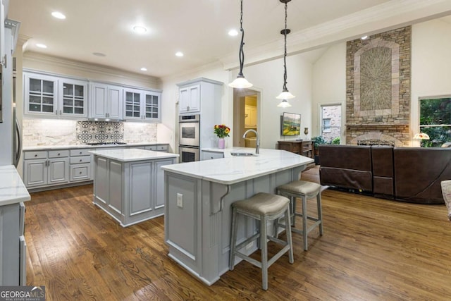8970 Moor Park Run, Duluth, GA 30097 - kitchen featuring gray cabinetry, a kitchen island, decorative backsplash, open floor plan, and stainless steel double oven