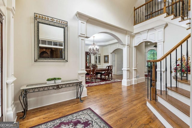 8970 Moor Park Run, Duluth, GA 30097 - foyer featuring arched walkways, decorative columns, wood finished floors, stairs, and a towering ceiling