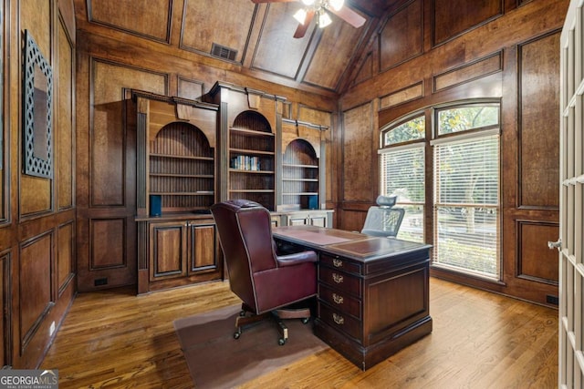 8970 Moor Park Run, Duluth, GA 30097 - home office featuring a decorative wall, ceiling fan, wood walls, light wood-style floors, and built in shelves
