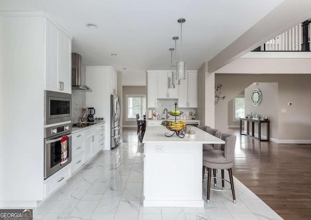 1270 Mccannon Morris Rd, Hull, GA 30646 - kitchen with appliances with stainless steel finishes, light countertops, wall chimney range hood, baseboards, and a kitchen bar