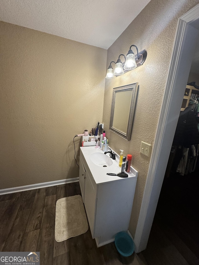353 Mosley Rd, Vidalia, GA 30474 - bathroom with wood finished floors, vanity, a textured wall, baseboards, and a walk in closet