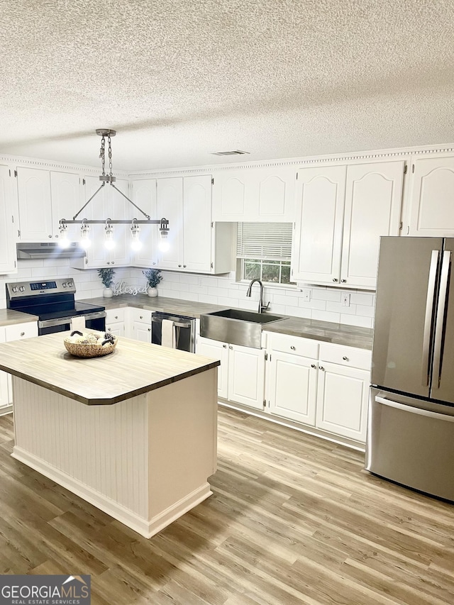 305 Lancelot Ln, Dublin, GA 31021 - kitchen featuring appliances with stainless steel finishes, a sink, under cabinet range hood, butcher block counters, and light wood-style flooring
