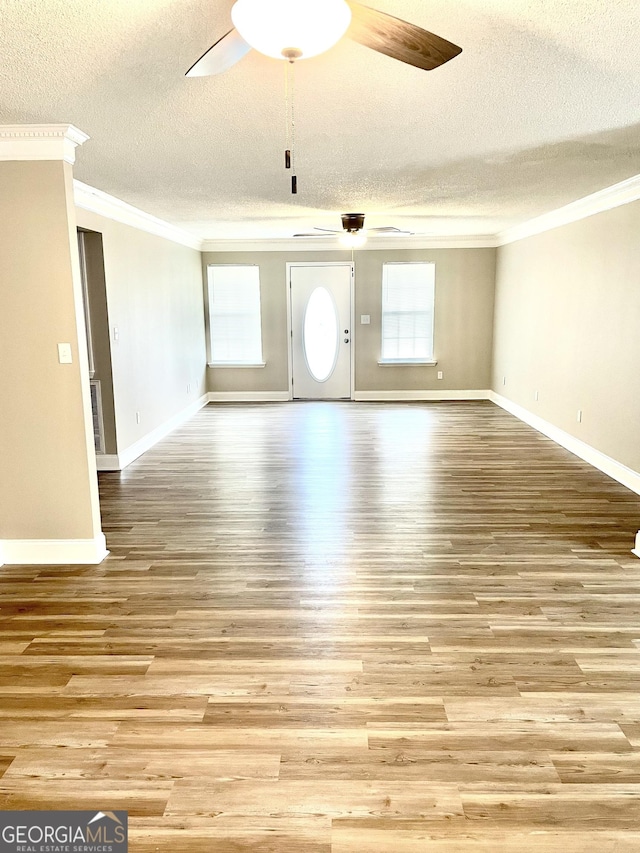 305 Lancelot Ln, Dublin, GA 31021 - unfurnished living room featuring crown molding, a textured ceiling, a ceiling fan, light wood finished floors, and baseboards
