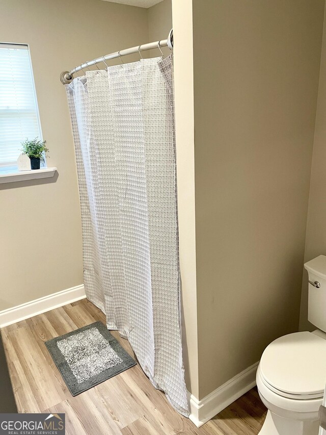 305 Lancelot Ln, Dublin, GA 31021 - bathroom with toilet, wood finished floors, a shower with shower curtain, and baseboards