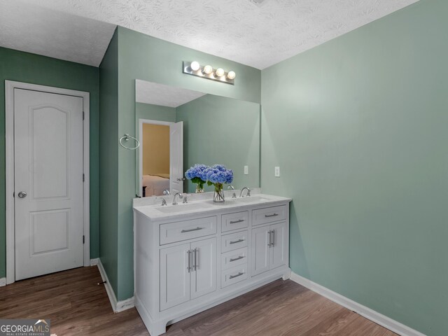 300 Furrow Creek Ct, Jackson, GA 30233 - bathroom with wood finished floors, baseboards, double vanity, and a textured ceiling