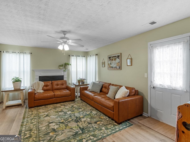 300 Furrow Creek Ct, Jackson, GA 30233 - living room featuring light wood finished floors, a ceiling fan, a fireplace, and a textured ceiling