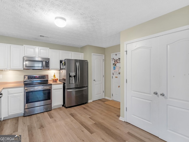 300 Furrow Creek Ct, Jackson, GA 30233 - kitchen featuring appliances with stainless steel finishes, light wood finished floors, light countertops, white cabinetry, and a textured ceiling