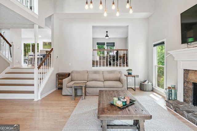 1005 Wellers Ct, Roswell, GA 30076 - living area featuring a stone fireplace, stairway, wood finished floors, baseboards, and a high ceiling