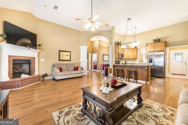 201 Loudon Hill Dr, Warner Robins, GA 31088 - living area featuring arched walkways, light wood-style floors, ceiling fan, a brick fireplace, and baseboards