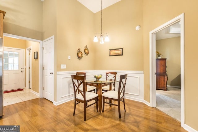 201 Loudon Hill Dr, Warner Robins, GA 31088 - dining space featuring high vaulted ceiling, light wood-style flooring, a chandelier, wainscoting, and baseboards
