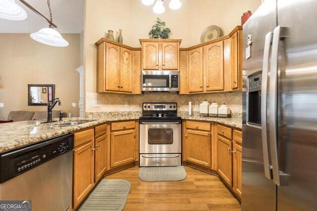 201 Loudon Hill Dr, Warner Robins, GA 31088 - kitchen featuring appliances with stainless steel finishes, a sink, tasteful backsplash, light wood-type flooring, and light stone counters