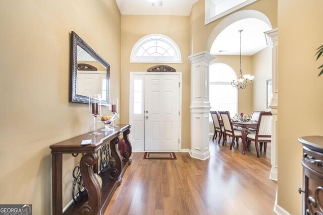 201 Loudon Hill Dr, Warner Robins, GA 31088 - foyer featuring decorative columns, wood finished floors, a chandelier, a towering ceiling, and arched walkways