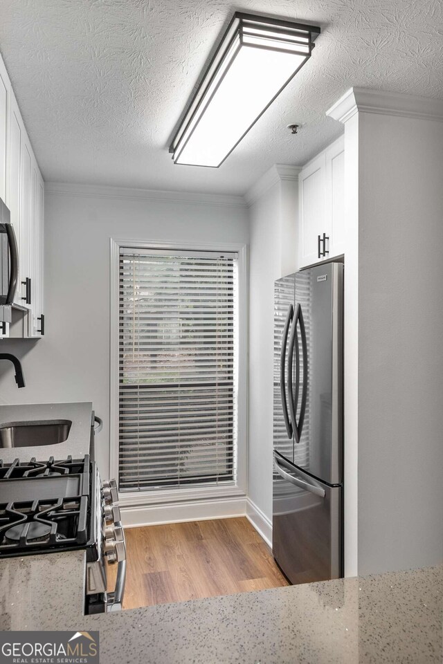 1603 Cumberland Ct, Smyrna, GA 30080 - kitchen featuring stainless steel appliances, a sink, white cabinets, ornamental molding, and light stone countertops