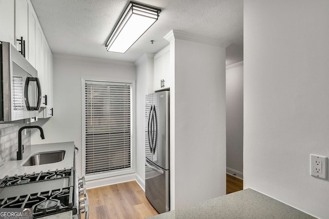1603 Cumberland Ct, Smyrna, GA 30080 - kitchen with stainless steel appliances, crown molding, white cabinetry, light wood-style floors, and a textured ceiling