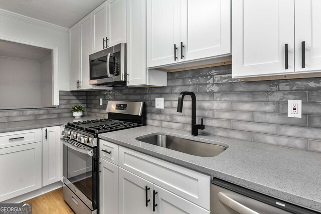 1603 Cumberland Ct, Smyrna, GA 30080 - kitchen with stainless steel appliances, a sink, white cabinets, light stone counters, and crown molding