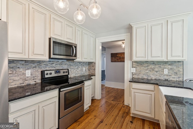 1382 6th Ave, Auburn, GA 30011 - kitchen featuring stainless steel appliances, tasteful backsplash, light wood-style flooring, and dark stone counters