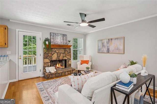 835 Navajo, Covington, GA 30016 - living room featuring crown molding, light wood-style flooring, a stone fireplace, and ceiling fan