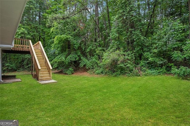 835 Navajo, Covington, GA 30016 - view of grassy yard with stairs, a wooden deck, and a view of trees