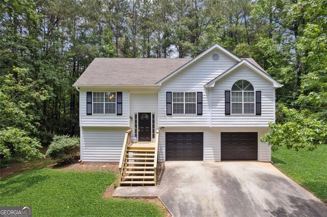 835 Navajo, Covington, GA 30016 - raised ranch with driveway, an attached garage, a front yard, and view of wooded area
