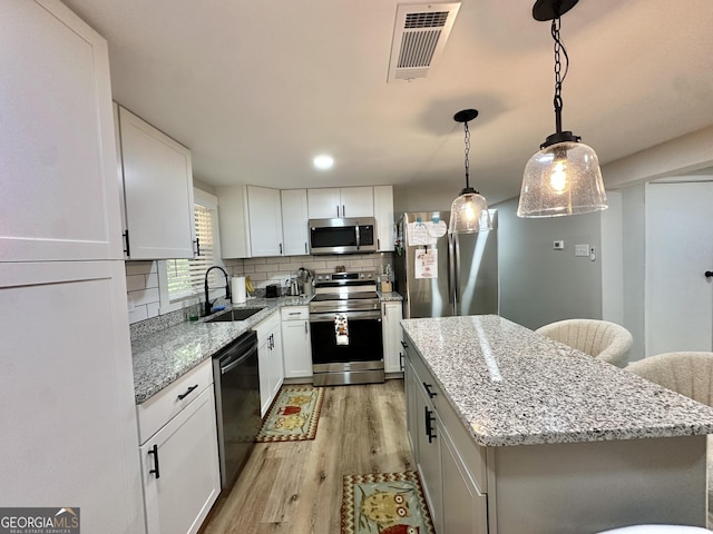 2165 S River Rd, Franklin, GA 30217 - kitchen with appliances with stainless steel finishes, a sink, light wood finished floors, a kitchen island, and backsplash