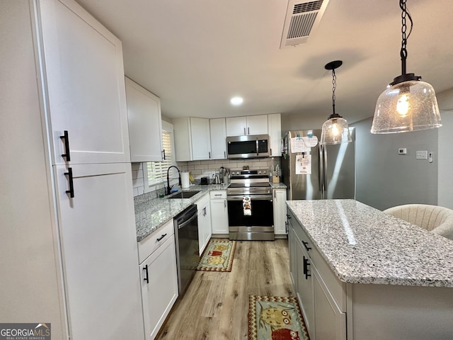 2165 S River Rd, Franklin, GA 30217 - kitchen featuring appliances with stainless steel finishes, a sink, light wood finished floors, backsplash, and a center island