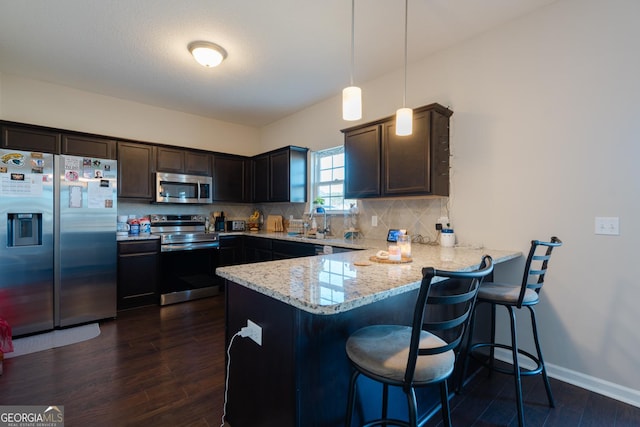 247 Morgan Field Blvd, Ludowici, GA 31316 - kitchen with appliances with stainless steel finishes, a peninsula, a sink, tasteful backsplash, and dark wood-style floors