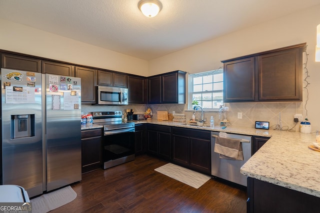 247 Morgan Field Blvd, Ludowici, GA 31316 - kitchen with stainless steel appliances, a sink, dark wood-style flooring, dark brown cabinetry, and light stone countertops