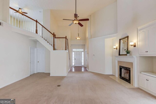 3585 Berkeley Park Ct, Duluth, GA 30096 - unfurnished living room featuring a high ceiling, a ceiling fan, light colored carpet, a fireplace, and baseboards