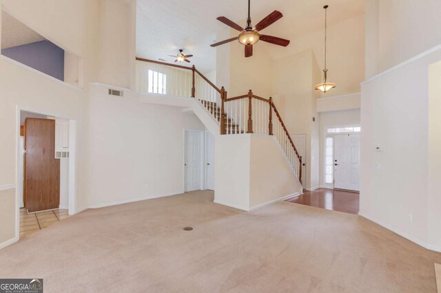 3585 Berkeley Park Ct, Duluth, GA 30096 - unfurnished living room featuring a high ceiling, carpet, stairway, a ceiling fan, and healthy amount of natural light