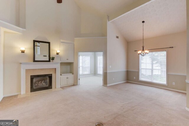 3585 Berkeley Park Ct, Duluth, GA 30096 - unfurnished living room with high vaulted ceiling, a fireplace with flush hearth, a chandelier, light colored carpet, and plenty of natural light