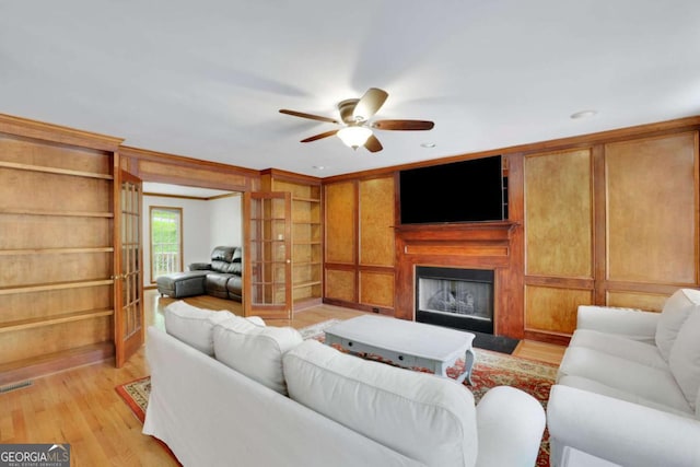 1925 Stonewyck Ct, Cumming, GA 30041 - living room featuring a ceiling fan, light wood finished floors, a fireplace, and built in shelves