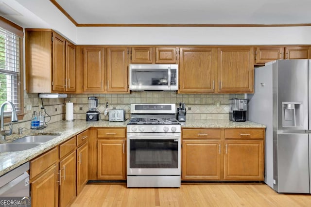 1925 Stonewyck Ct, Cumming, GA 30041 - kitchen with stainless steel appliances, brown cabinets, light wood-style floors, tasteful backsplash, and ornamental molding