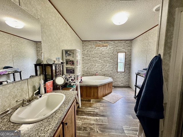 342 Wellington Dr, Byron, GA 31008 - bathroom with a textured ceiling, wood finished floors, vanity, a garden tub, and ornamental molding