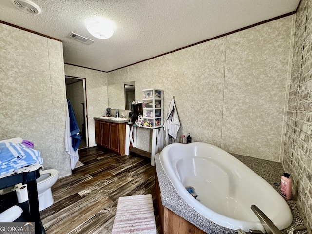 342 Wellington Dr, Byron, GA 31008 - bathroom featuring wood finished floors, a bath, vanity, toilet, and a textured ceiling